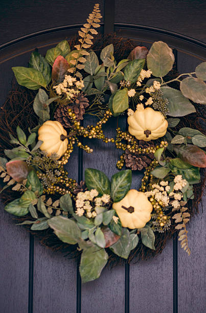 istock Ornate fall wreath with white pumpkins hanging on front door 613675798