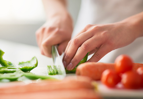 Closeup shot of a young woman chopping vegetables in the kitchen
