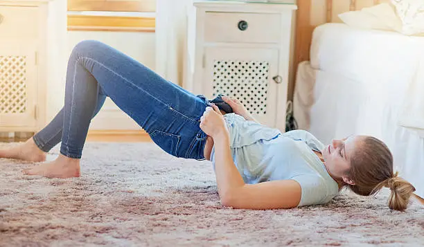 Shot of a young woman struggling to fit into her jeans at home