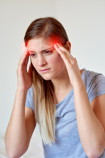 Cropped shot of a young woman suffering from a headache highlighted in glowing red