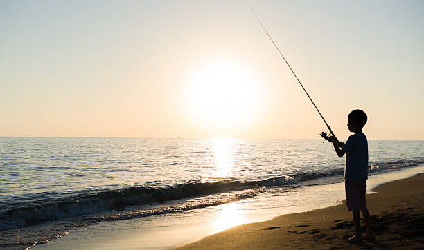 istock young boy fishing by sunset 613684288