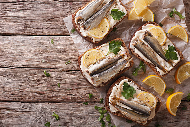 Toasts with sprats, cream cheese and lemon horizontal top view