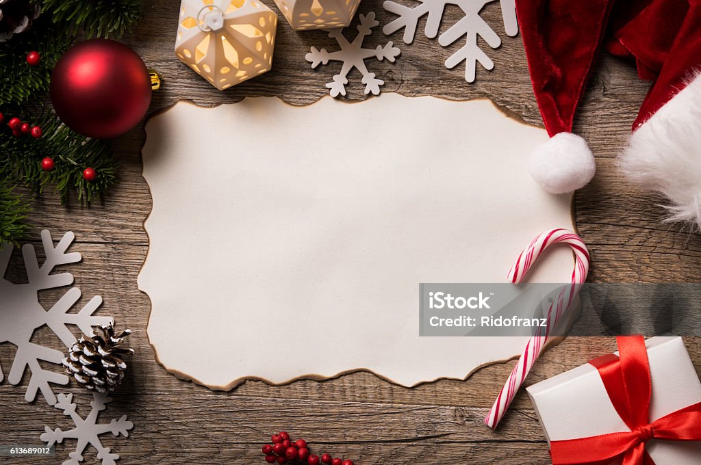 Letter to Santa Claus High angle view of empty letter on wooden table with christmas decoration. Top view of empty xmas wish list with little gift present and santa claus hat on wooden background. Santa Claus Stock Photo