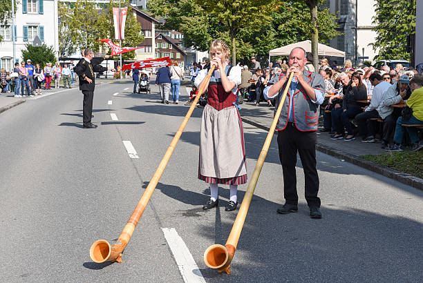 People wearing traditional clothes and playing the alphorn at En Ennetbuergen, Switzerland - September 24, 2016: People wearing traditional clothes and playing the alphorn at Ennetbuergen on the Swiss alps alpenhorn stock pictures, royalty-free photos & images