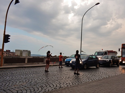 Benevento, Campania, Italy - August 30, 2016: group of young jugglers at the traffic light at the intersection with the Heat bridge, while still entertaining the motorists waiting for shots on the green. After a brief show of about fifteen seconds they approach the car to collect a few coins.