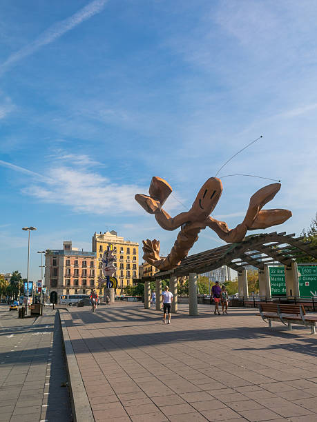 Barcelona, Spain - October 5, 2016: passersby on a sunny day on October 5, 2016, on the Walk 'Moll de la Fusta', on the coast of the city of Barcelona. In the background the monuments 'Gamba' & 'Barcelona's Head'