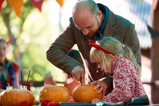 Father showing his daughter how to make Jack o'Lantern
