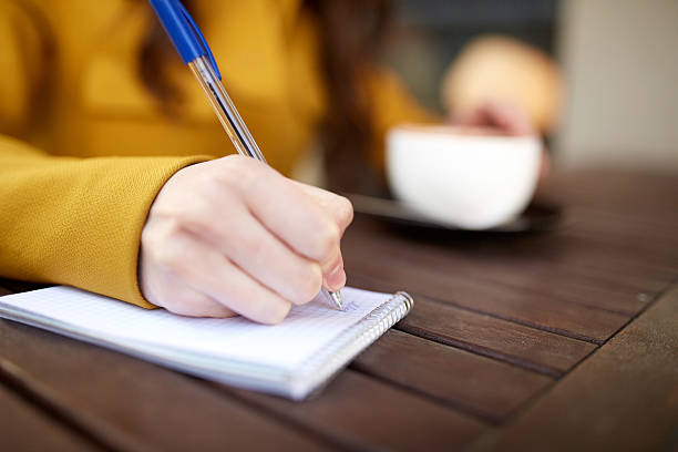 istock close up of hand writing to notebook at cafe 613754656
