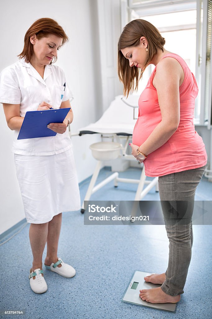 Nurse weighing pregnant woman in office Nurse weighing pregnant woman in ambulances Doctor Stock Photo