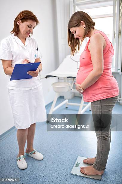 Nurse Weighing Pregnant Woman In Office Stock Photo - Download Image Now - Doctor, Pregnant, Weight Scale