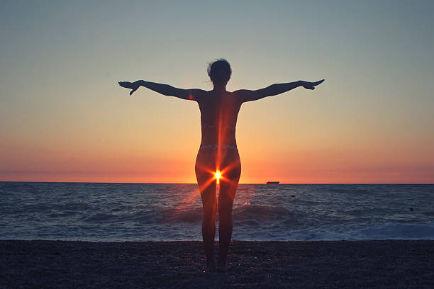 Strong confidence woman open arms under the sunrise at seaside