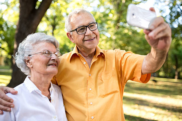 istock Happy senior couple taking selfie in park 613757400