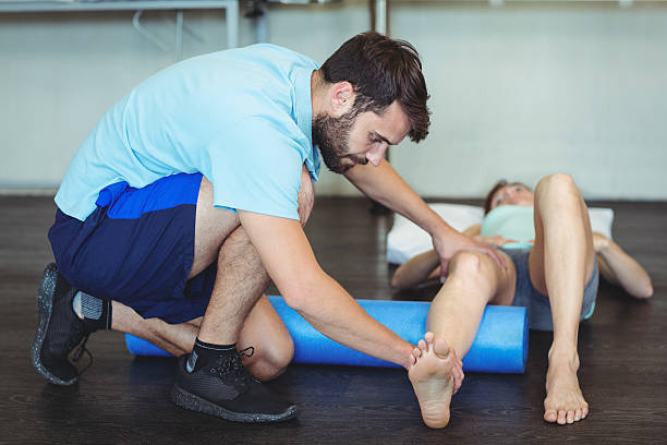 istock Physiotherapist doing leg therapy to a woman using foam roll 613758838