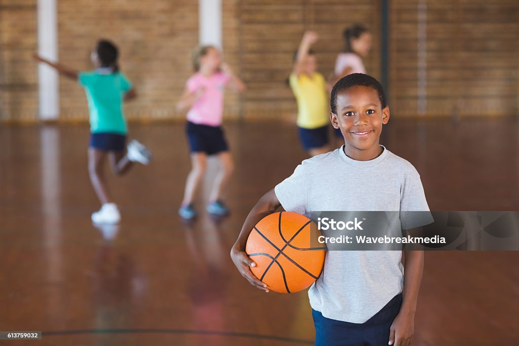 Niño de pie con pelota en cancha de baloncesto - Foto de stock de Niño libre de derechos