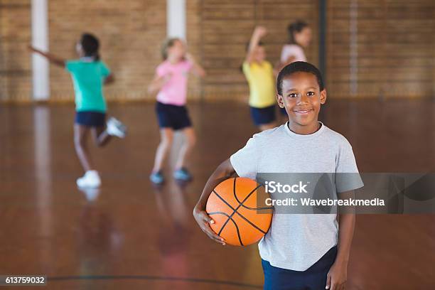 Niño De Pie Con Pelota En Cancha De Baloncesto Foto de stock y más banco de imágenes de Niño - Niño, Baloncesto, Gimnasio