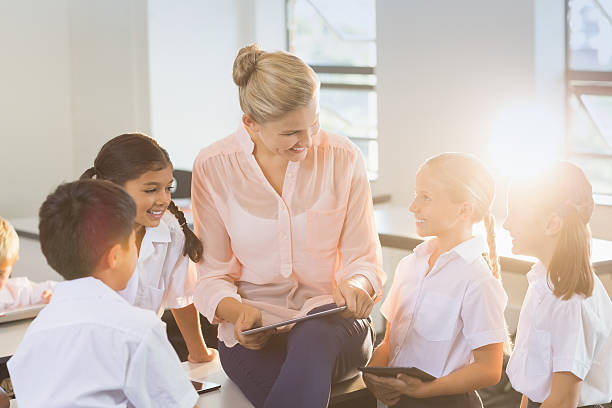 istock Teacher teaching kids on digital tablet 613759176