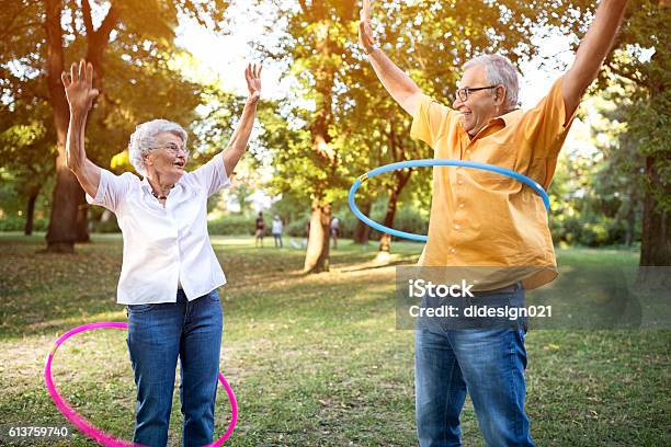 Feliz Pareja De Ancianos Divertido Jugando Hulahop En El Parque Foto de stock y más banco de imágenes de Tercera edad