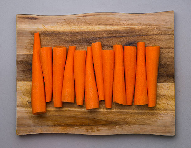 peeled carrots on a wooden tray, gray background