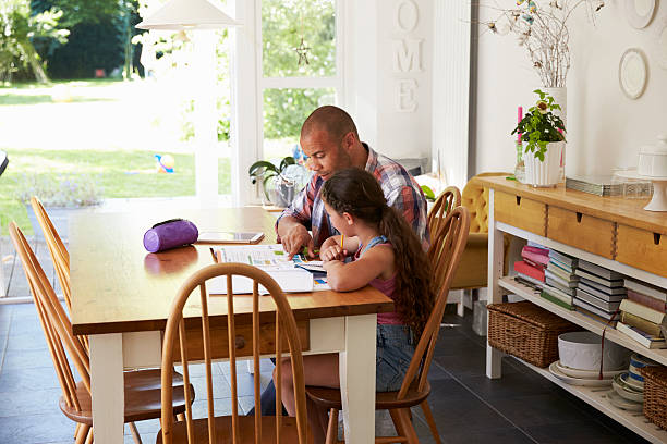 istock Father Helping Daughter With Homework At Table 613764956