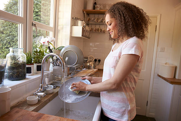 mujer de pie en el fregadero de la cocina lavando - lavar los platos fotografías e imágenes de stock