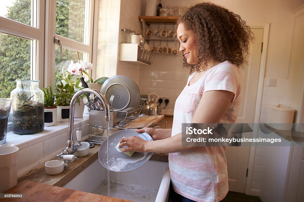 Woman Standing At Kitchen Sink Washing Up Washing Dishes Stock Photo