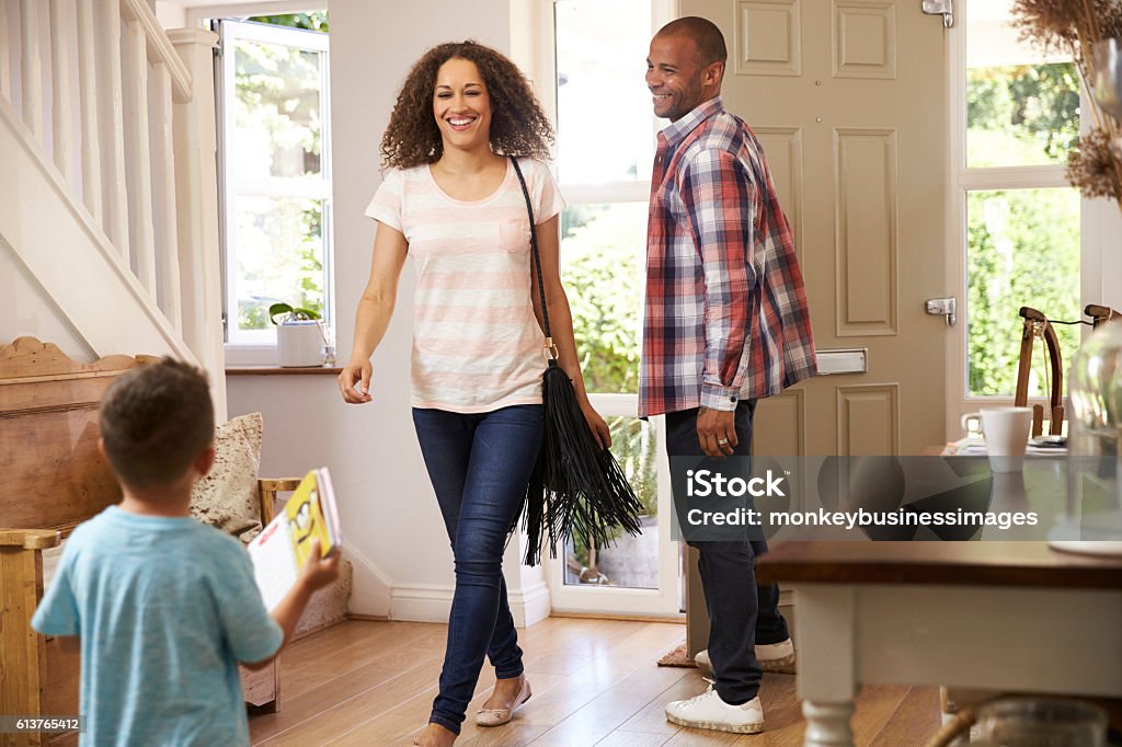 Father Opens Front Door For Mother Returning Home From Work Arrival Stock Photo