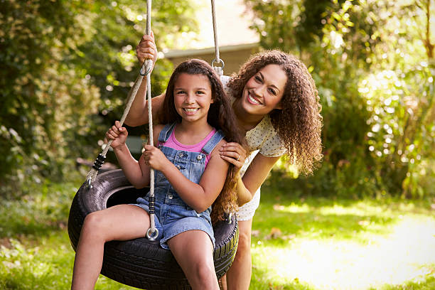 mãe empurrando filha em balanço de pneu no jardim - tire swing - fotografias e filmes do acervo