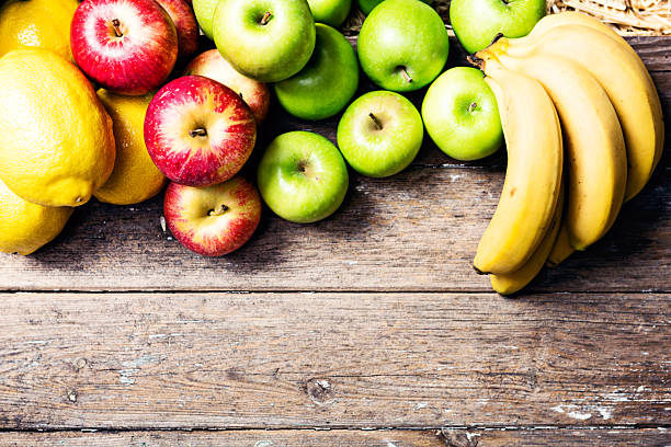 istock Cornucopia of fresh fruit forms upper border on weathered wood 613766540