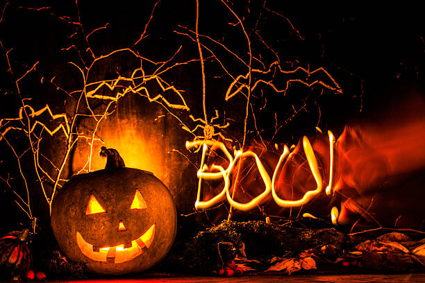 istock Spooky halloween pumpkin background with light draw BOO 613767376