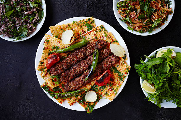 Middle East Food Culture - Shish Kebab Turkish Adana kebab and salads on a dark surface. turkish culture stock pictures, royalty-free photos & images