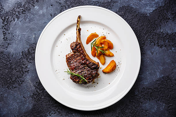 istock Grilled beef rib on plate with potato wedges 613769682