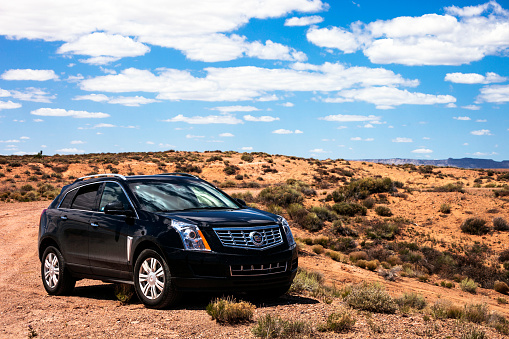 Many Farms, Arizona, USA - April 29, 2016: Black SUV Cadillac SRX parked in the middle of desert landscape.