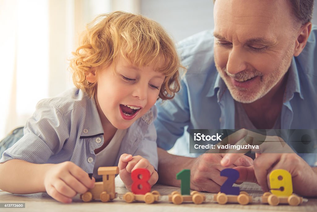 Grandpa and grandson Handsome grandpa and grandson are talking and smiling while playing with toys together at home Grandparent Stock Photo