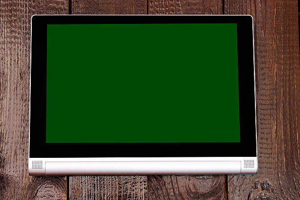 istock Tablet with isolated green screen, on the brown wooden table. 613774898