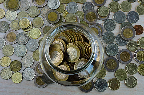 istock Coins in and around a glass jar on table 613778968
