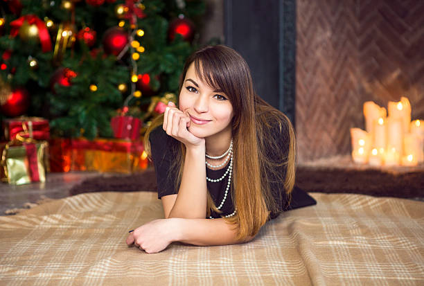 Happy smiling woman on floor the by Christmas tree