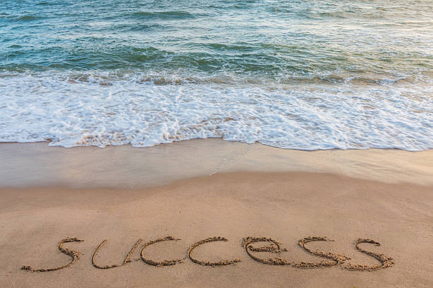 istock alphabet letters success handwritten in sand on beach 613786336