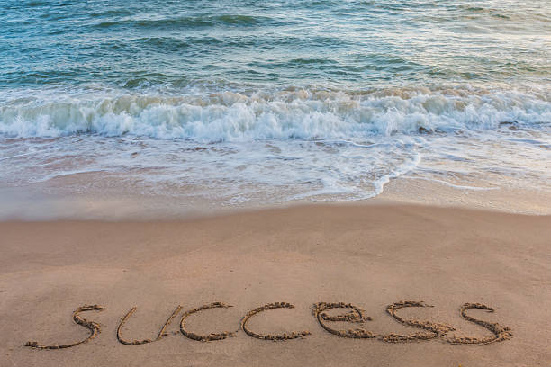 istock alphabet letters success handwritten in sand on beach 613786400