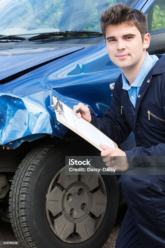 Auto Workshop Mechanic Inspecting Car And Filling In Repair Estimate Auto Workshop Mechanic Inspecting Damage To Car And Filling In Repair Estimate Repairing Stock Photo