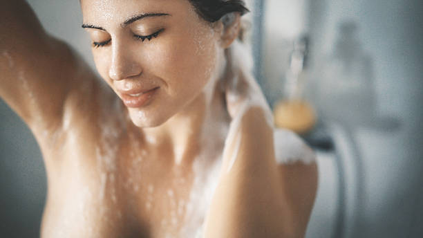 Pleasure of a shower. Closeup top view of attractive mid 20's woman taking a shower in her bathroom after a long exhausting day at work or college. She's gently washing her hair and skin, makeup still on. washing hair stock pictures, royalty-free photos & images