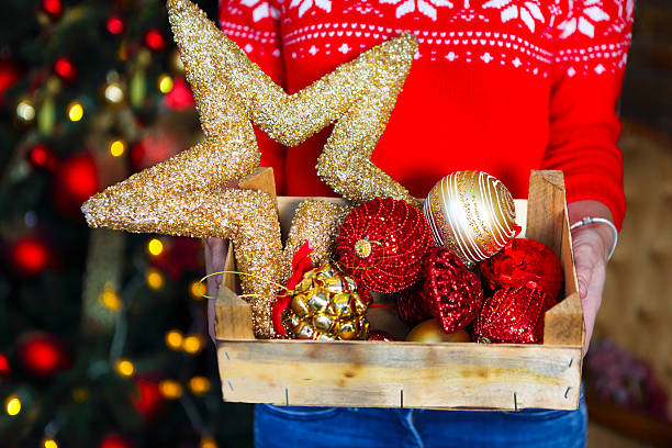 frau hält box mit vielen weihnachtsdekorationen - christmas tree bead humor stock-fotos und bilder