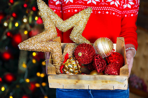 woman holds box with a lot of christmas decorations - christmas tree bead humor imagens e fotografias de stock