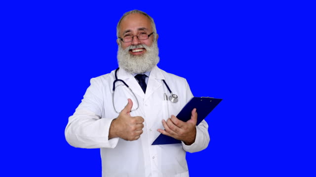adult senior doctor  writes on a clipboard on a blue background.