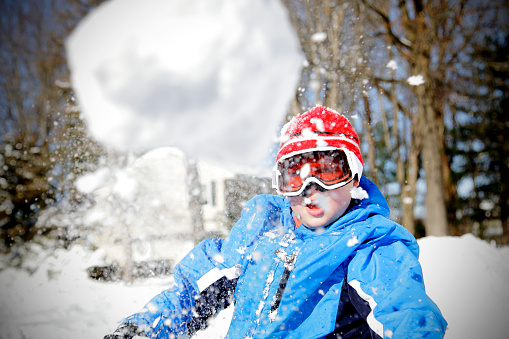 Boy with autism and ADHD takes his aim and throws a snowball at the the camera. Shot taken a moment before impact.