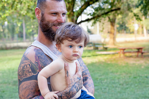 istock tattooed father have fun with his son in the park 613865136