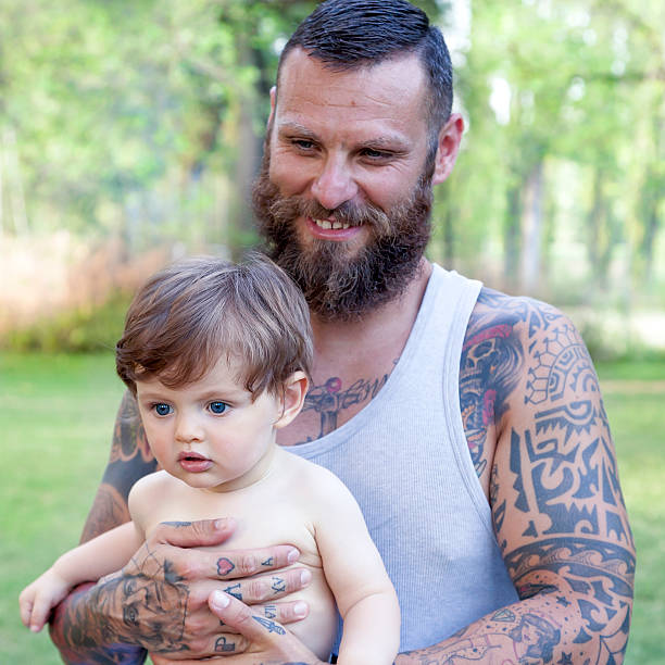 istock tattooed father have fun with his son in the park 613865344