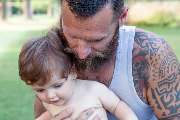 istock tattooed father have fun with his son in the park 613865562