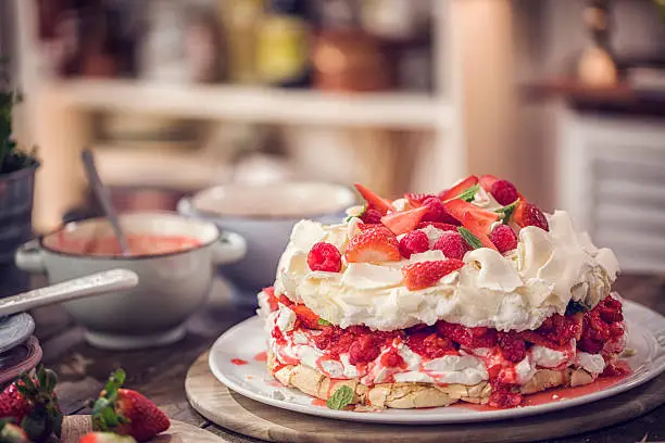 Berry Pavlova Cake with fresh strawberries, raspberries, mint leaves and whipped cream.