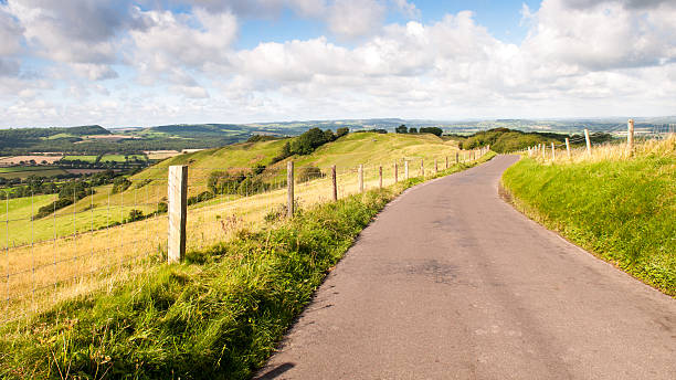 On Bulbarrow Hill A single-track country lane runs along the ridge of Bulbarrow Hill in the rolling agricultural landscape of England's Dorset Downs. blackmore vale stock pictures, royalty-free photos & images