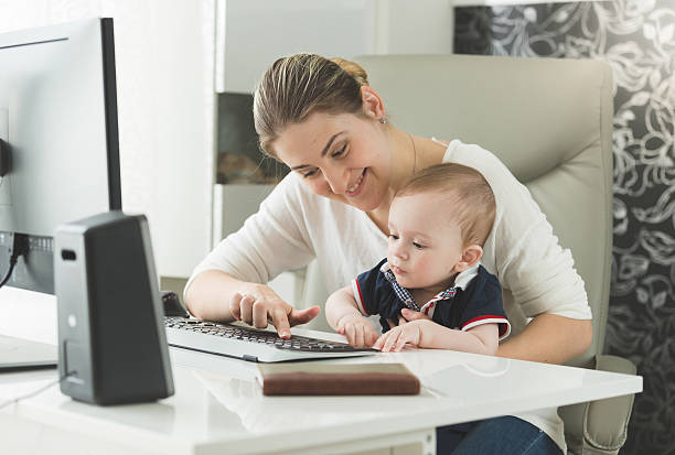 istock Elegant woman teaching her baby how to use computer 613870418